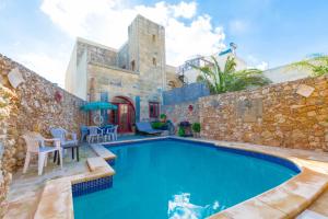 a house with a swimming pool and a stone wall at Stunning 3 bedroom Farmhouse with pool in Xagħra