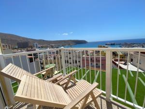 a balcony with two wooden chairs and the ocean at Apartamentos Ohana - Edificio Tonillo in Los Cristianos