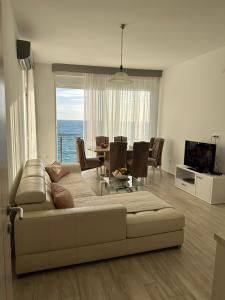 a living room with a couch and a table and a television at Paradise beachfront view 2 in Dobra Voda