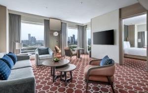 a hotel room with a couch and chairs and a television at Four Seasons Hotel Mumbai in Mumbai