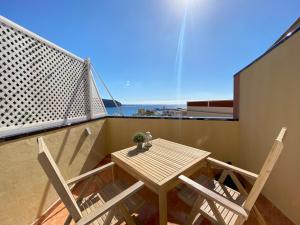 a balcony with a wooden table and two chairs at Apartamentos Ohana - Edificio Tonillo in Los Cristianos