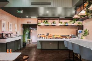 a restaurant with a counter and tables and chairs at Hotel Indigo London - Kensington, an IHG Hotel in London