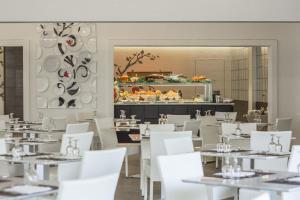 una sala da pranzo con tavoli bianchi e sedie bianche di Costa Rey Wellness & Spa a Costa Rei