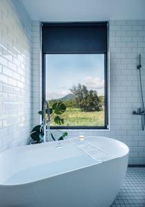 a white bath tub in a bathroom with a window at Lainandao Villa in Hengchun