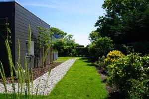 een tuin met gras en bloemen naast een gebouw bij Texel Boogaloo in De Koog