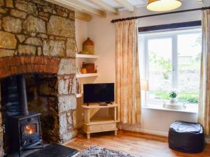 sala de estar con chimenea de piedra y TV en Bellringers Cottage, Llandegla, en Llandegla