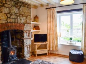 a living room with a stone fireplace and a television at Bellringers Cottage, Llandegla in Llandegla