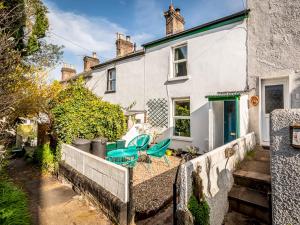 Pass the Keys Cottage with garden tucked away in central Exeter في إكسيتير: منزل أبيض مع كراسي زرقاء في الفناء