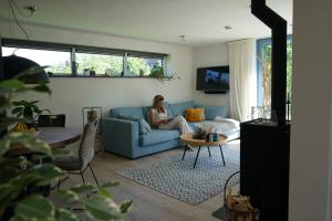 a woman sitting on a blue couch in a living room at Texel Boogaloo in De Koog