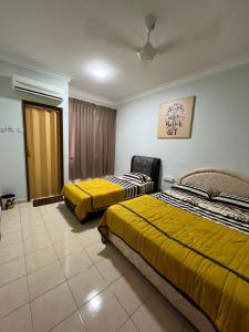 two beds in a hotel room with yellow beds at MY HOMESTAY BAHAU in Bahau