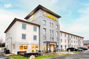 a white building with a gold sign on it at B&B Hotel Kassel-Süd in Kassel