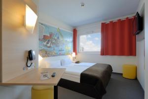Cette chambre comprend un lit, un bureau et une fenêtre. dans l'établissement B&B Hotel Hamburg-Harburg, à Hambourg