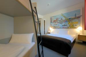 a bedroom with two bunk beds and a painting on the wall at B&B Hotel Hamburg-Harburg in Hamburg