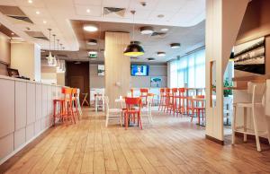 a restaurant with orange chairs and a bar with a counter at B&B Hotel Katowice Centrum in Katowice