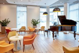 een piano in een kamer met tafels en stoelen bij B&B Hotel Katowice Centrum in Katowice