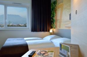 a bedroom with two beds and a desk with a laptop at B&B Hotel Graz City-Süd in Graz