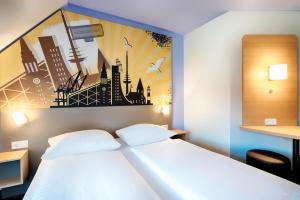 B&B Hotel Kiel-Holstenbrücke في كيل: غرفة نوم بسرير ابيض مع لوحة على الحائط