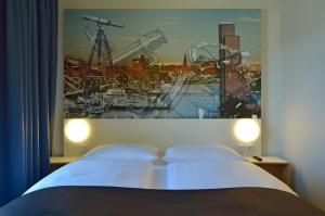 een slaapkamer met een bed met een schilderij aan de muur bij B&B Hotel Kiel-Wissenschaftspark in Kiel