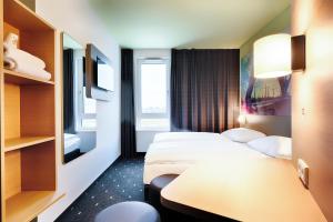 een hotelkamer met 2 bedden en een tafel bij B&B Hotel Kehl in Kehl am Rhein