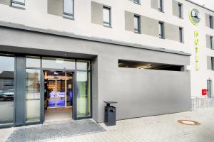 a building with glass doors and a trash can outside at B&B Hotel Kehl in Kehl am Rhein