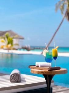 a table with a drink and towels next to a pool at NOOE Maldives Kunaavashi in Fulidhoo