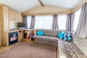 a living room with a couch and a television at 8 Berth Spacious Dog Friendly Caravan, Near Great Yarmouth In Norfolk Ref 10004g in Belton