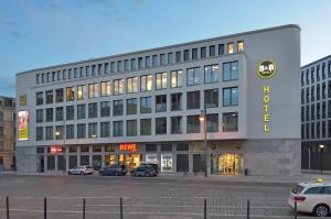 een groot gebouw met auto's geparkeerd op een parkeerplaats bij B&B Hotel Halle (Saale) in Halle an der Saale