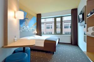 a hotel room with a bed and a desk and a window at B&B Hotel Hannover-City in Hannover
