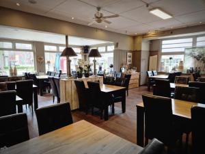 a restaurant with wooden tables and chairs and windows at Hof van Sellingen in Sellingen