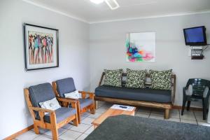 a living room with a couch and chairs and a tv at Lodge Laske Nakke in Lydenburg