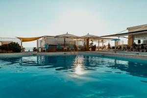 einen Pool mit blauem Wasser, Tischen und Sonnenschirmen in der Unterkunft Hotel Saline in Palinuro