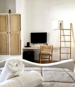 a bedroom with a bed and a desk with a television at Hôtel Palombaggia in Porto-Vecchio