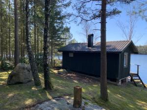a cabin on the shore of a lake with trees at Sävsjön in Mjöbäck
