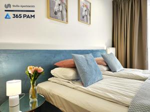 a bedroom with a bed with a blue headboard and a table at Resort Westin House - 365PAM in Kołobrzeg