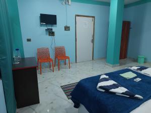 a bedroom with a bed and two chairs and a tv at Andaman Runway in Port Blair