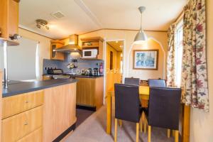 a kitchen and dining room with a table and chairs at Great Dog Friendly Caravan To Hire With Field Views In Norfolk Ref 10132b in Belton