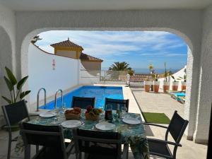 a table with food on top of a patio with a pool at Nerja Paradise Rentals - Villa Dos Ardillas in Nerja