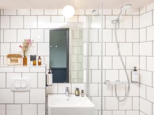 La salle de bains blanche est pourvue d'un lavabo et d'une douche. dans l'établissement Eklo Montpellier Centre Gare, à Montpellier