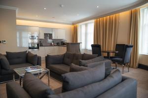 a living room with two couches and a kitchen at County Hotel & County Aparthotel Newcastle in Newcastle upon Tyne