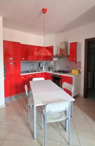 eine Küche mit roten Schränken sowie einem weißen Tisch und Stühlen in der Unterkunft Bicycle road in Imperia