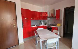 eine Küche mit roten Schränken sowie einem weißen Tisch und Stühlen in der Unterkunft Bicycle road in Imperia