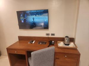 einen Schreibtisch mit einem TV an der Wand und einem Telefon in der Unterkunft HOTEL HERENCIA 625 formerly Abaca Suites in Locsin