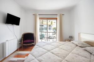 a bedroom with a bed and a television and a balcony at Corrente do Oudinot perto da praia in Gafanha da Nazaré