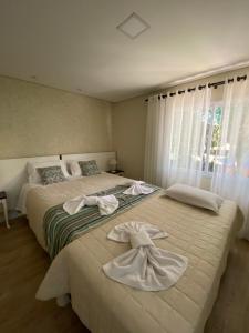 2 łóżka w sypialni z ręcznikami w obiekcie Ipê Amarelo Cama e Café w mieście Gramado