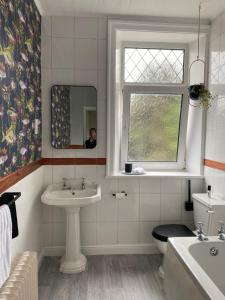 a bathroom with a sink and a toilet and a window at Cobble Cottage in Lindley