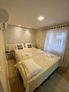 a hotel room with two beds with towels on them at Ipê Amarelo Cama e Café in Gramado