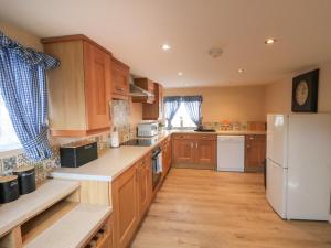 cocina con armarios de madera y nevera blanca en Rose Cottage, en Whitby