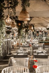 a restaurant with white tables and chairs and plants at Hospes Puerta de Alcalá, a Member of Design Hotels in Madrid