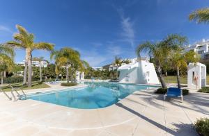 una piscina con palmeras y un edificio en Lagoon suites en Casares