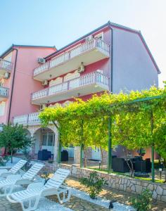 Ein rosafarbenes Gebäude mit einem Haufen Stühle davor. in der Unterkunft Villa Dalia in Mostar